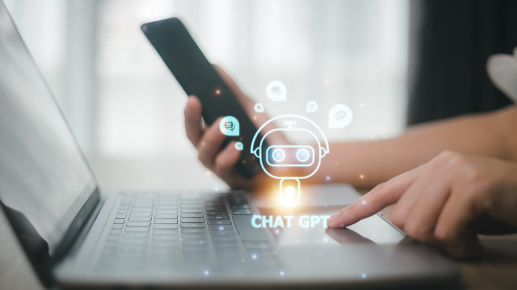 Image showing smartphone and laptop in use, with image of ChatGPT as a chatbot